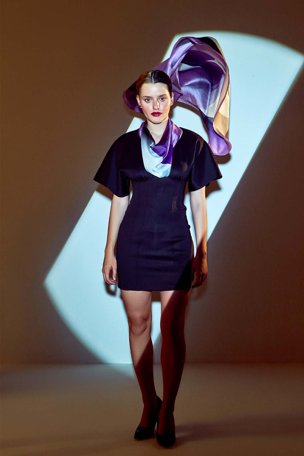 Model wearing Thánatos scented silk scarf in purple hues under dramatic lighting.