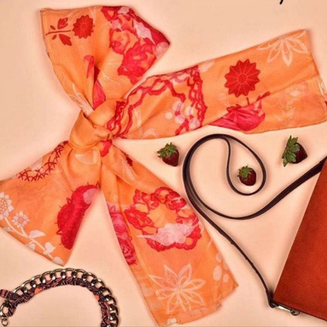 Flat lay of the Blush Cosmo scarf styled with accessories and strawberries, showcasing its luxury floral pattern.