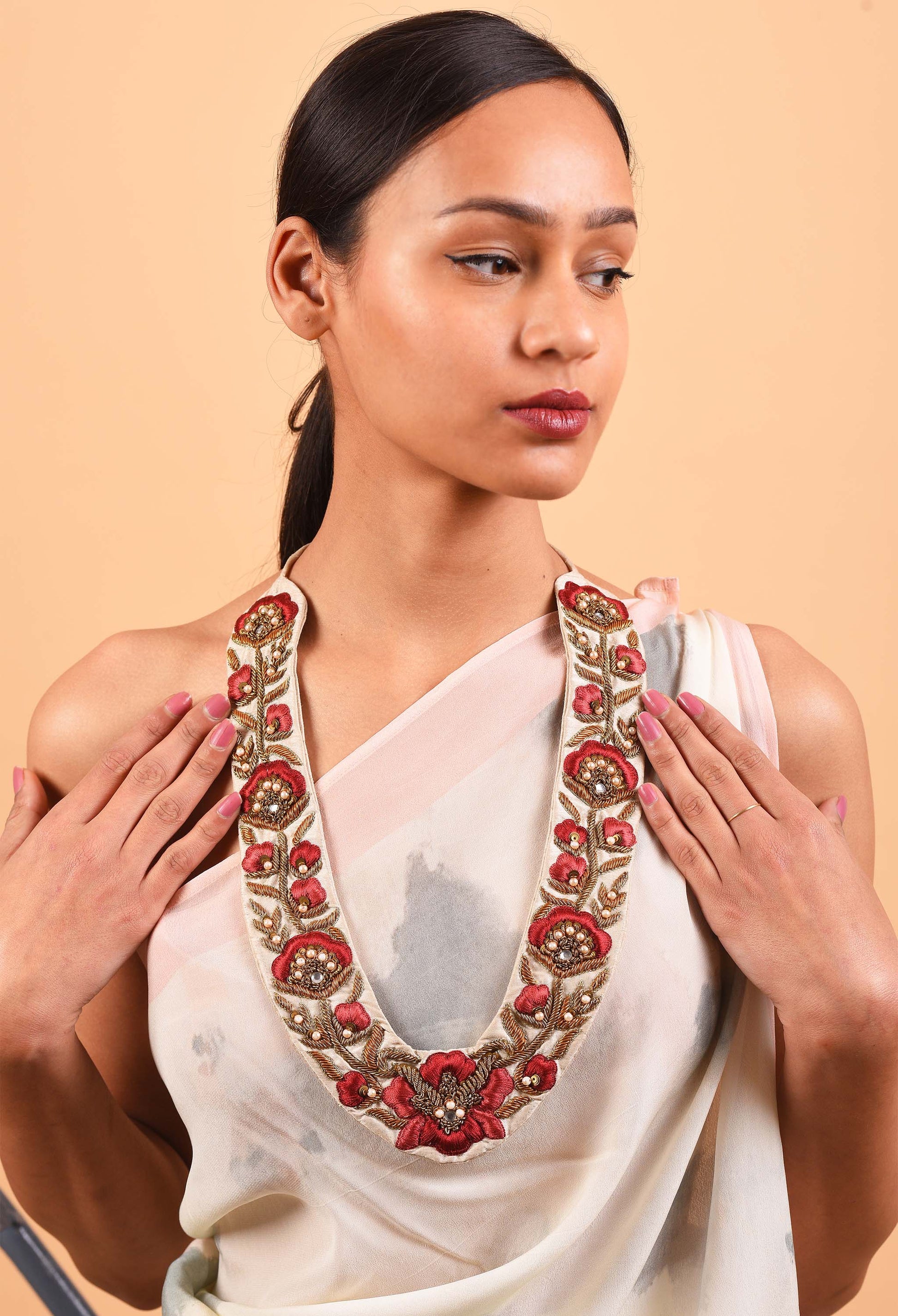 Model wearing Freeque's Crest fine jewelry necklace inspired by traditional Indian weaving, with intricate red floral designs.