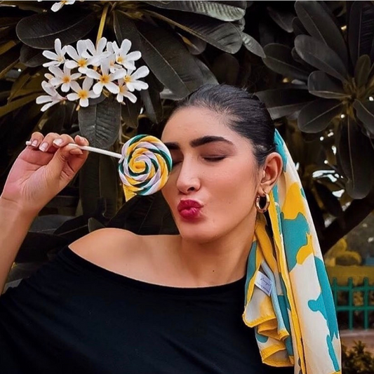 Model wearing Freeque's Lemony Blue Meringue scented stole with a playful lollipop, styled in a tropical setting