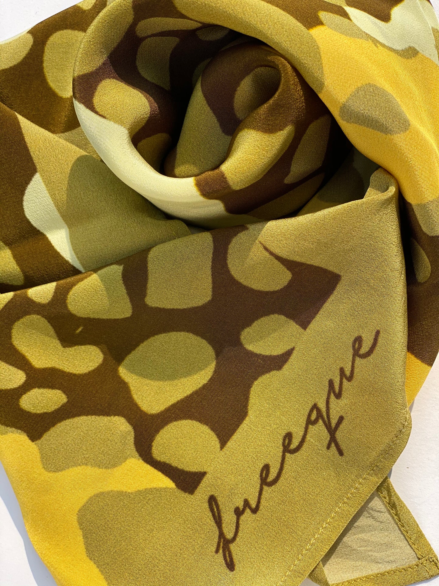 Close-up of Olive Island scented bandana fabric texture with Freeque logo.