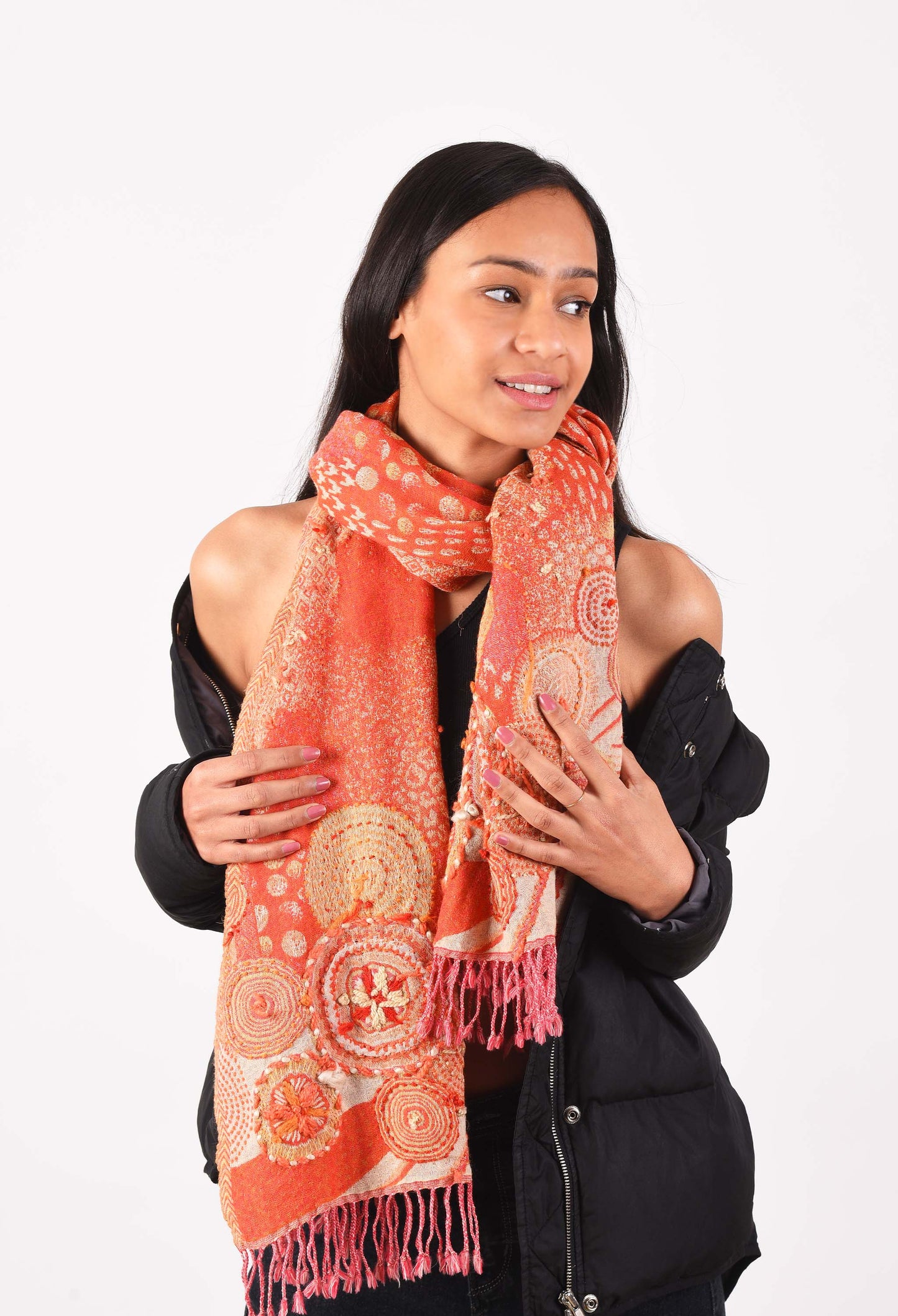 Woman modeling an orange camel wool stole with intricate embroidered patterns, styled gracefully over a black jacket.