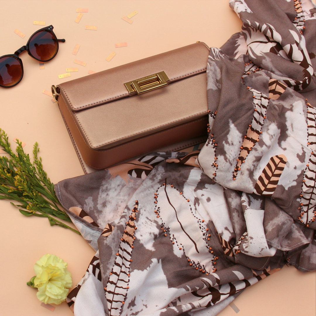 Luxury scented stole with feather and embroidery details next to handbag and sunglasses